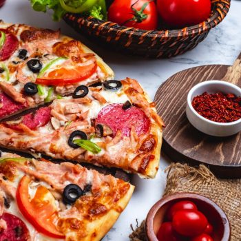 side-view-pizza-with-salami-ham-green-peppers-tomatoes-black-olives-cheese-table